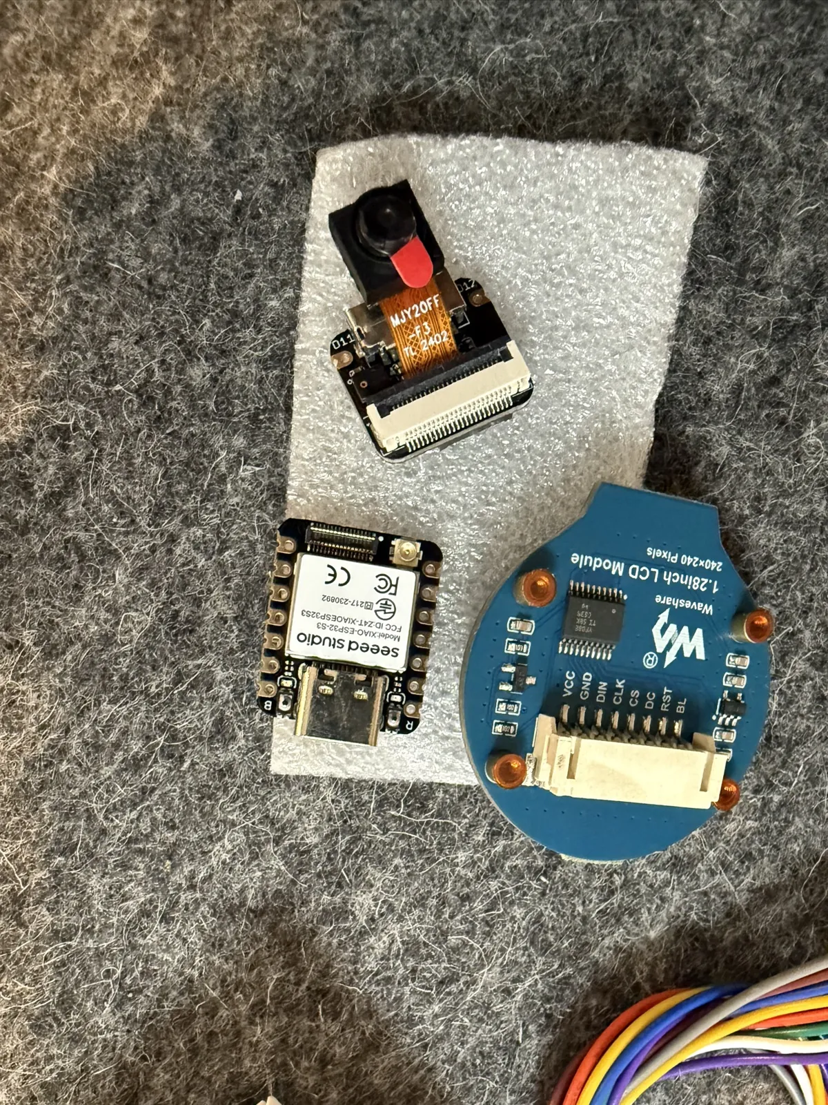 The camera, the XIAO board and the round screen laid out on a felt mat