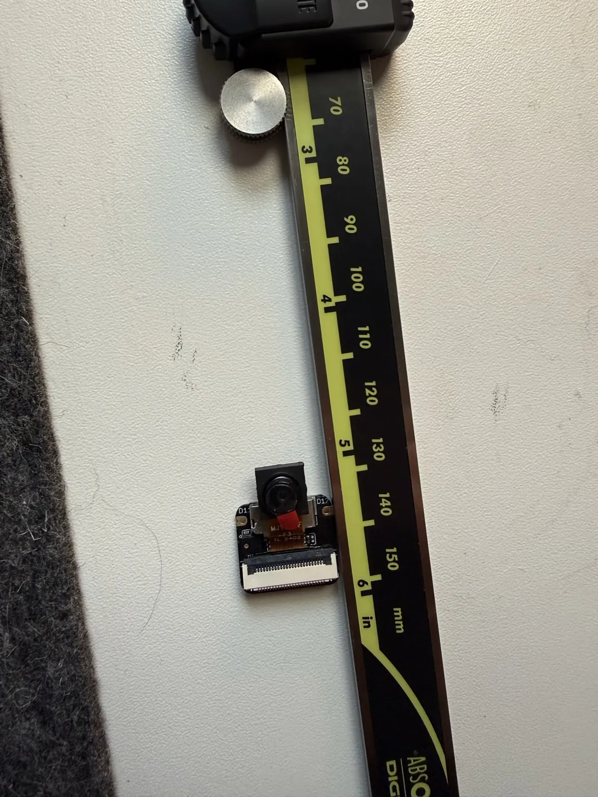 Digital calipers measuring the small camera module